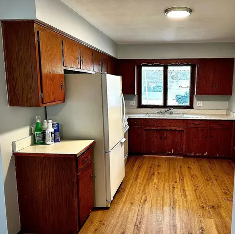 a kitchen with kitchen island granite countertop wooden cabinets a sink a stove and a refrigerator
