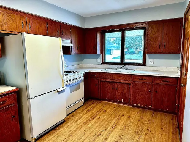 a kitchen with a refrigerator a stove and wooden cabinets