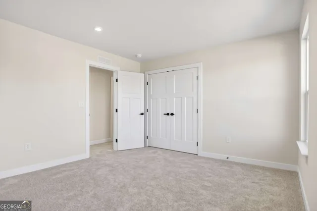 a view of an empty room with window and a bathroom