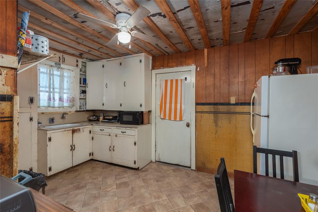 6473 West Highway 199 Springtown, TX 76082 - Photo 6 of 40 Kitchen with freestanding refrigerator, wooden walls, light countertops, black microwave, and ceiling fan