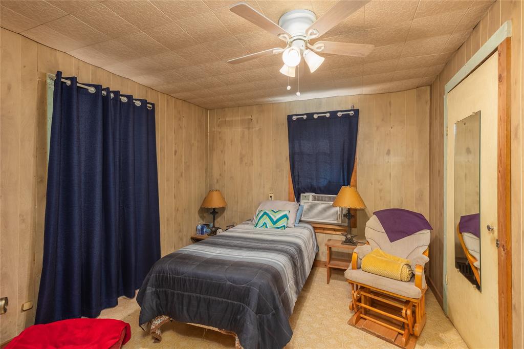 6473 West Highway 199 Springtown, TX 76082 - Photo 9 of 40 Bedroom featuring wood walls, a ceiling fan, and cooling unit