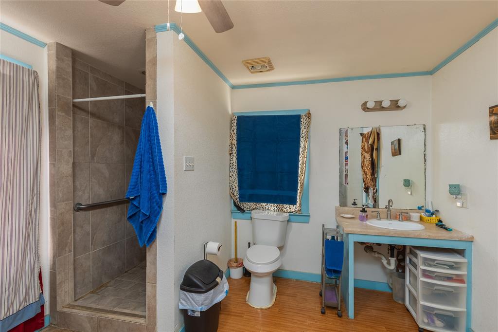 6473 West Highway 199 Springtown, TX 76082 - Photo 10 of 40 Full bathroom featuring a shower stall, wood finished floors, and a ceiling fan
