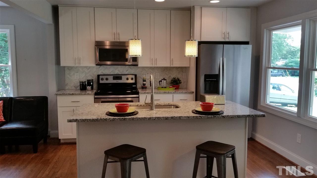 2318 Kennington Road Raleigh, NC 27610 - Photo 5 of 20 a kitchen with stainless steel appliances granite countertop a stove a refrigerator a sink and a dining table with wooden floor