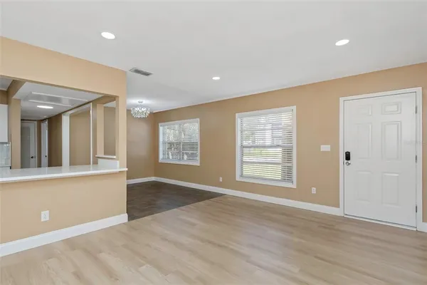 a view of an empty room with wooden floor and a window