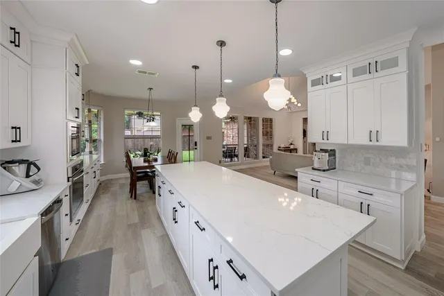 a large white kitchen with a large island oven
