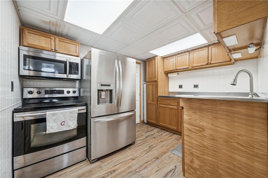 190 Urban Road Saltsburg, PA 15681 - Photo 30 of 44 a kitchen with stainless steel appliances granite countertop a refrigerator a stove a sink and a microwave oven with wooden floor