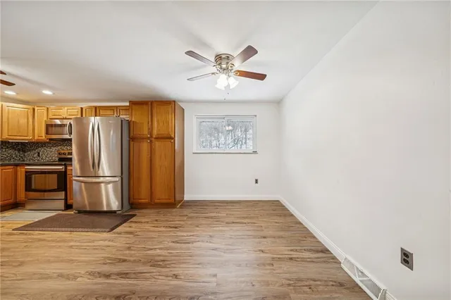 a view of kitchen with stainless steel appliances wooden floor and a window