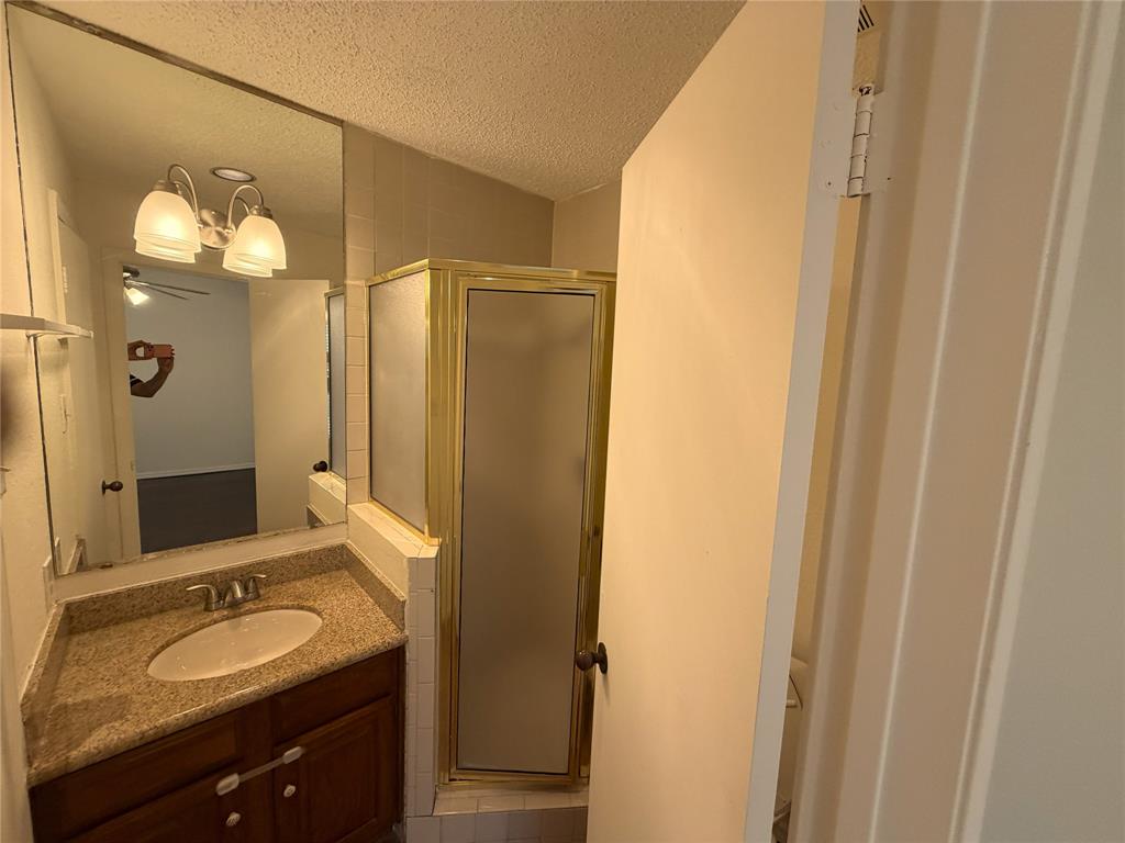 18240 Midway Road, Unit 206 Dallas, TX 75287 - Photo 15 of 16 Bathroom featuring a vanity with a light-toned stone-finish countertop, an oval undermount sink, and a dark wood-finish cabinet