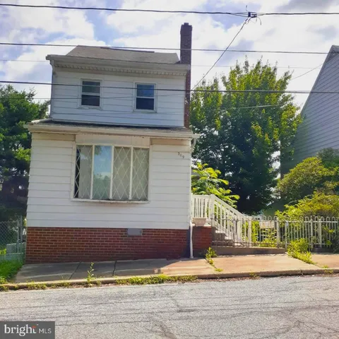 a view of a brick house with a yard and large tree
