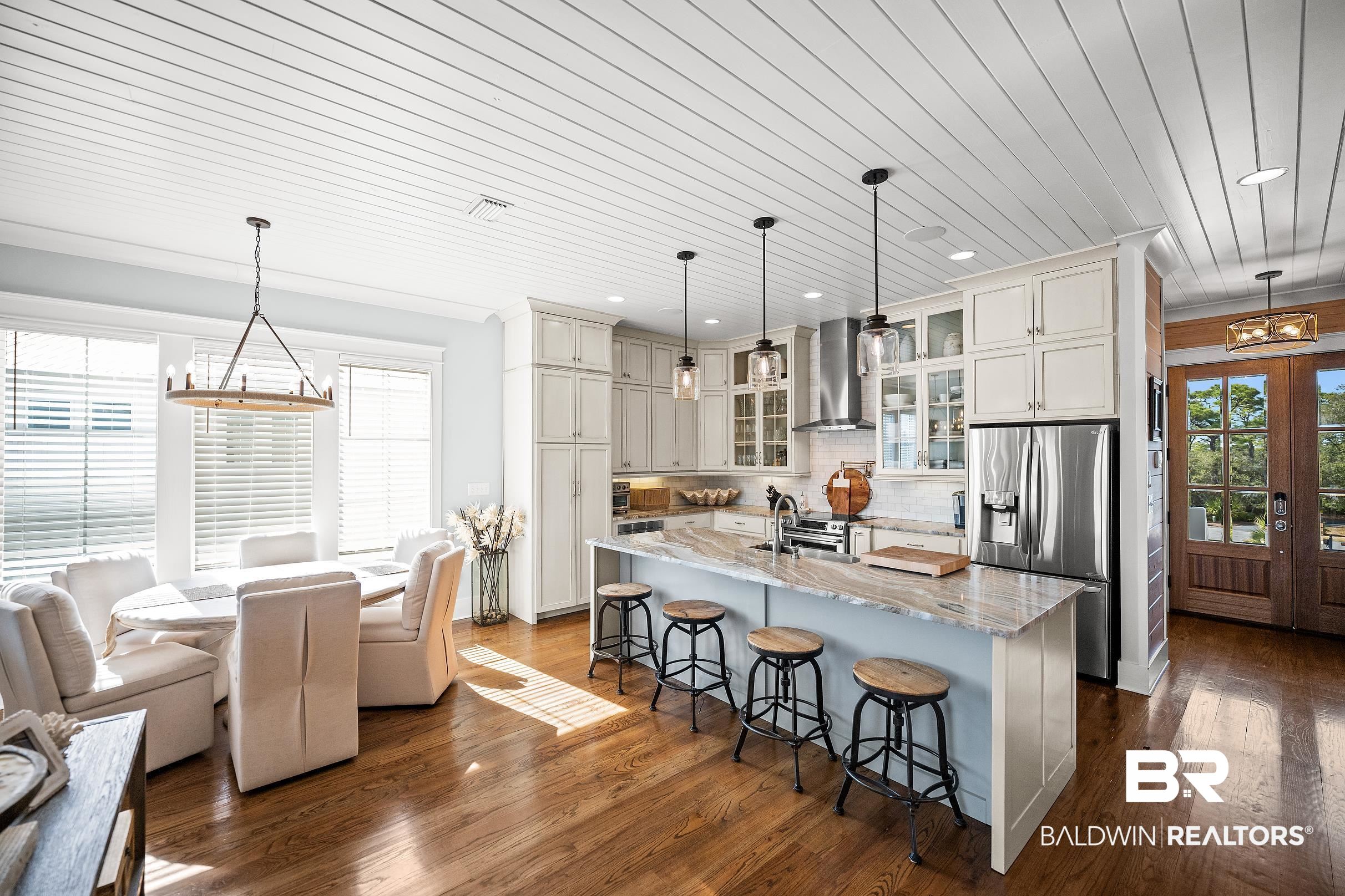 33186 Marlin Key Drive Orange Beach, AL 36561 - Photo 24 of 87 Kitchen featuring suspended lighting, glass fronted cabinets, stainless steel appliances, light stone countertops, and a center island with sink