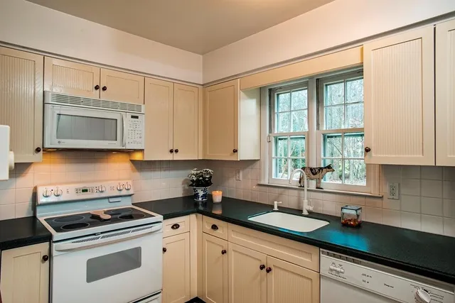 a kitchen with granite countertop white cabinets and white stainless steel appliances