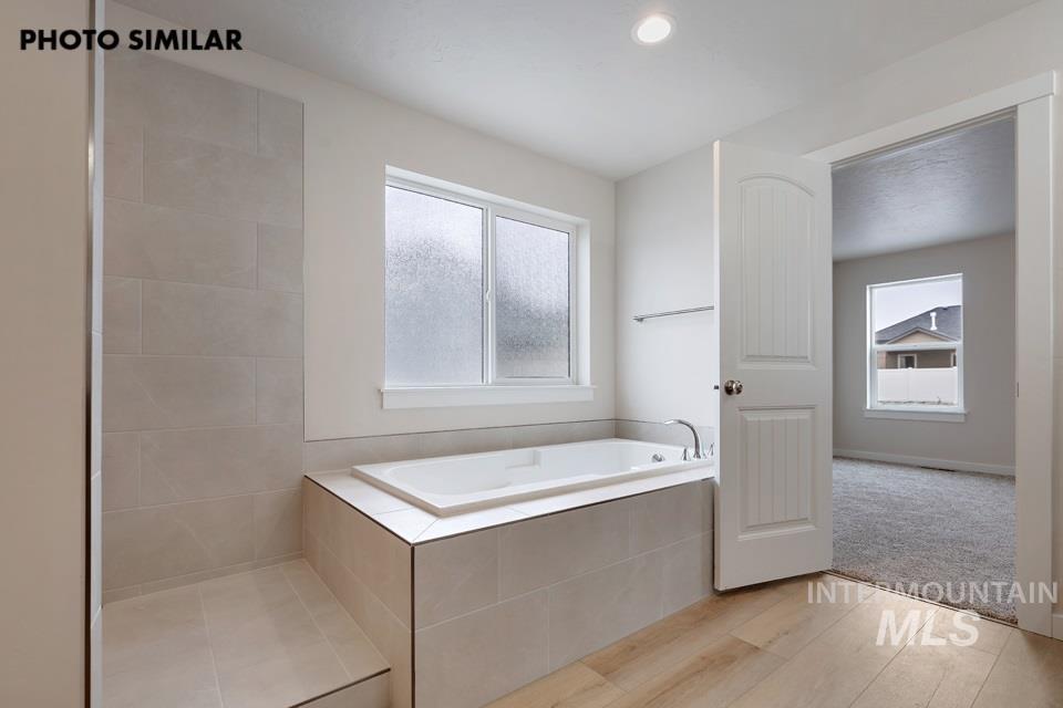 1645 Haystack Emmett, ID 83617 - Photo 18 of 33 Contemporary bathroom featuring a built-in soaking tub, large format tile surround, and a coordinating tiled shower with a step
