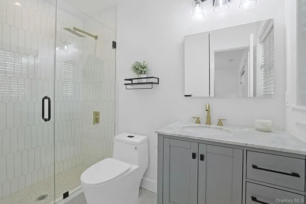 a bathroom with a toilet sink vanity granite and shower
