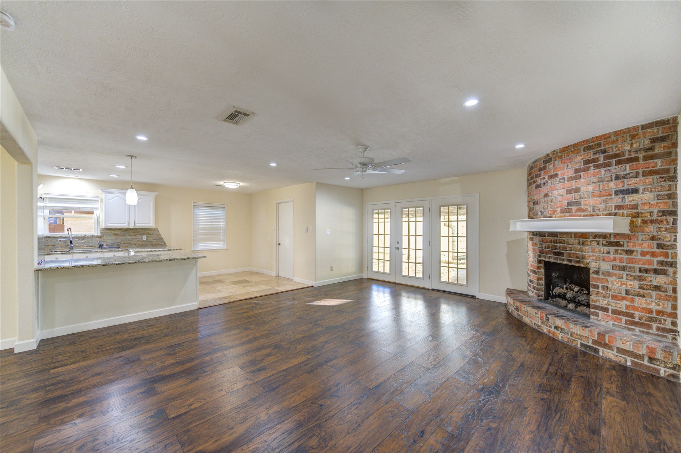 8826 Rowan Lane Houston, TX 77036 - Photo 9 of 26 a view of an empty room with wooden floor and a kitchen