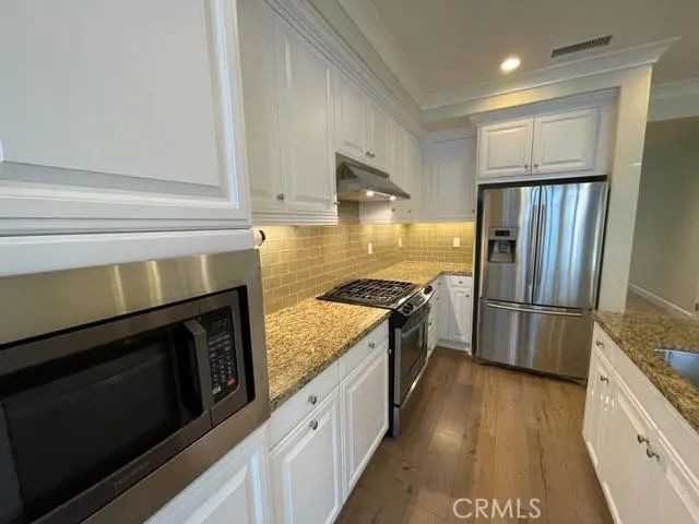 a kitchen with granite countertop a refrigerator stove and oven