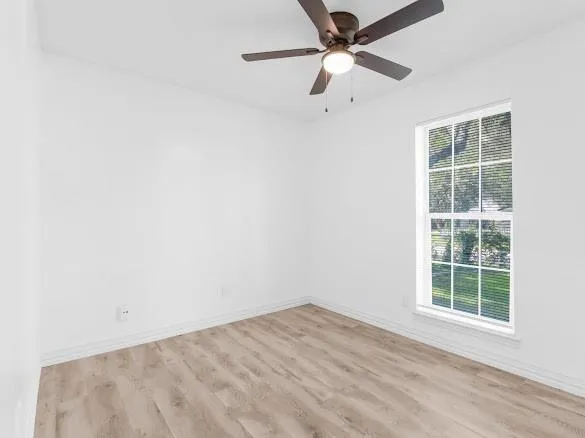 an empty room with a window and a fan