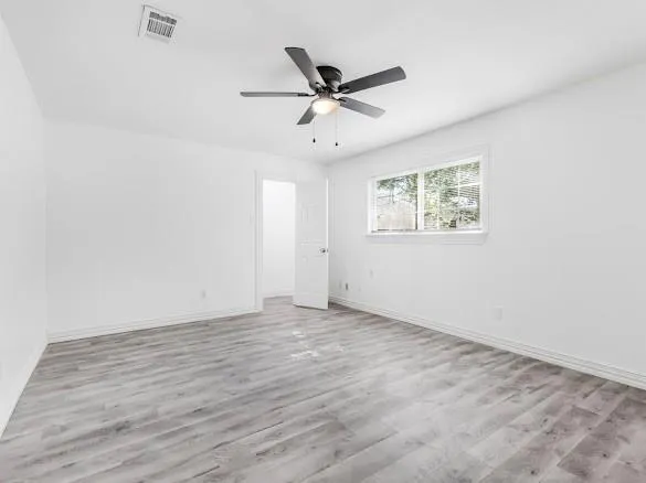 an empty room with wooden floor and ceiling fan