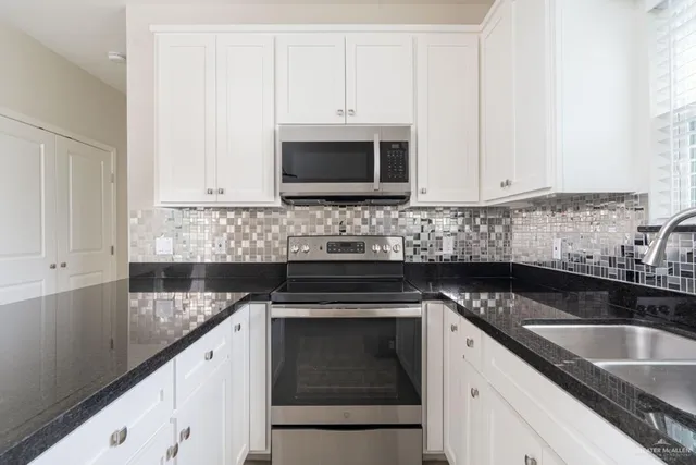 a kitchen with granite countertop white cabinets and a sink