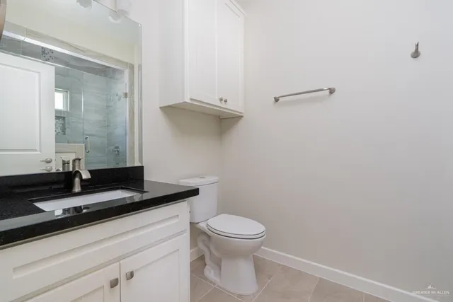 a bathroom with a granite countertop toilet and a sink