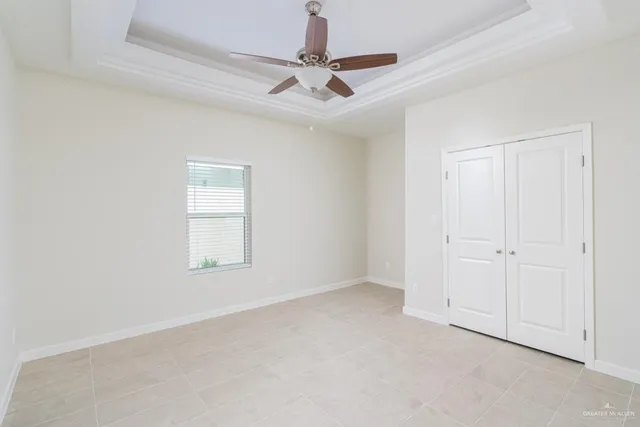 an empty room with a ceiling fan and windows