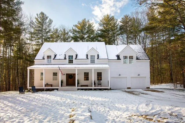 a view of a white house with a large tree in front of it
