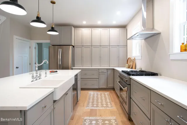 a kitchen with a stove a refrigerator a sink dishwasher with a dining table and chairs with wooden floor