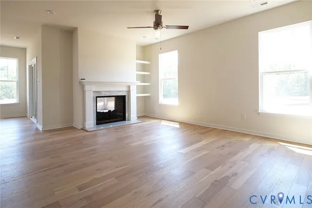 an empty room with wooden floor windows and a fireplace