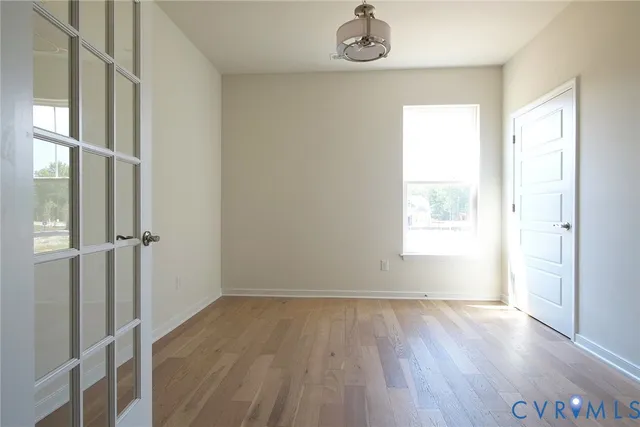 an empty room with wooden floor and window
