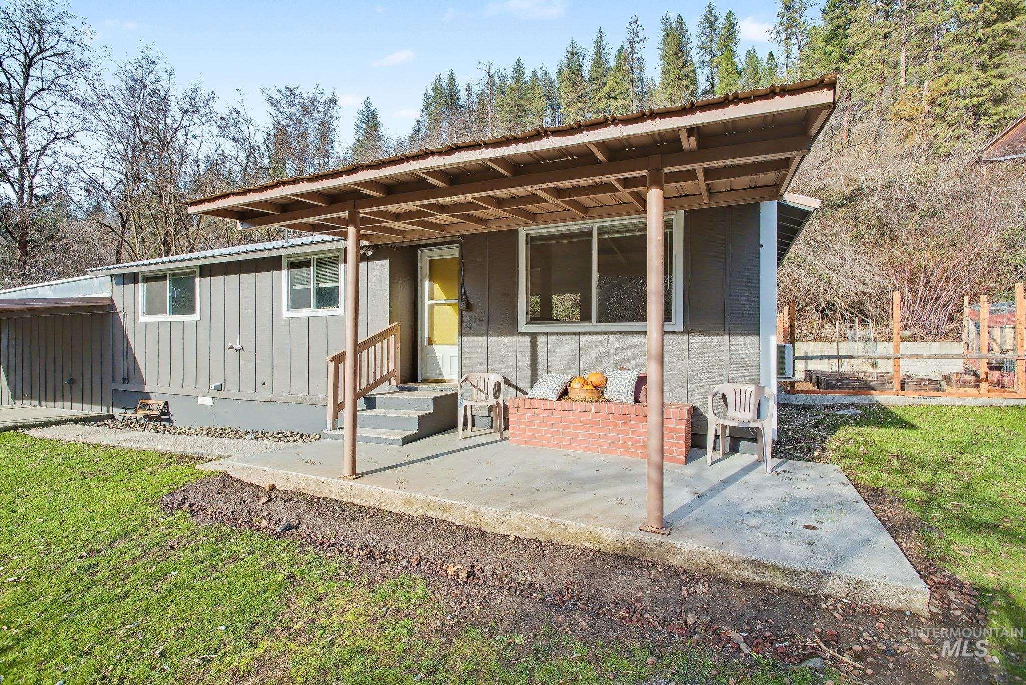 150 Elm Street Orofino, ID 83544 - Photo 23 of 36 Exterior property featuring board and batten siding, a covered concrete patio, a red brick planter, and a terraced backyard