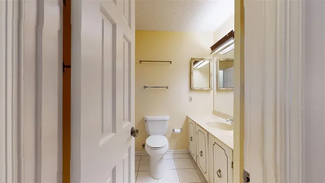 a bathroom with a granite countertop toilet a sink and a mirror