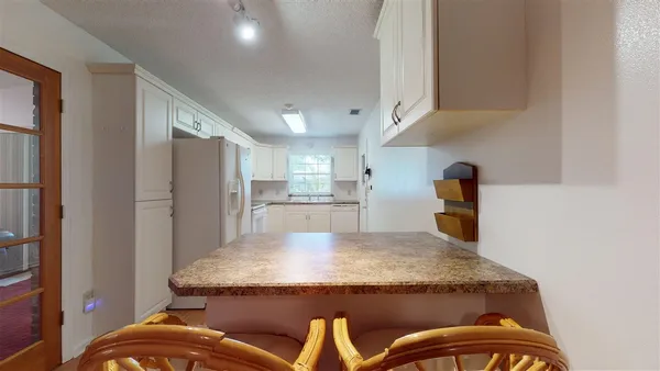 a kitchen with granite countertop sink and refrigerator