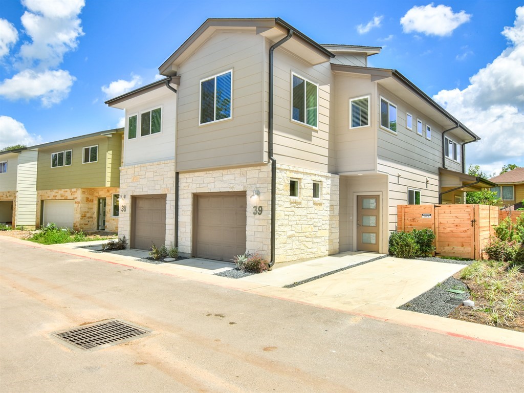 6800 Menchaca Road, Unit 39 Austin, TX 78745 - Photo 1 of 16 Multi-level modern townhomes showcase siding and stone accents alongside integrated garage entries.