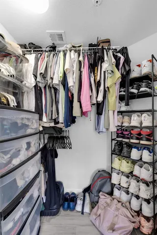 a view of walk in closet with clothes and shoes