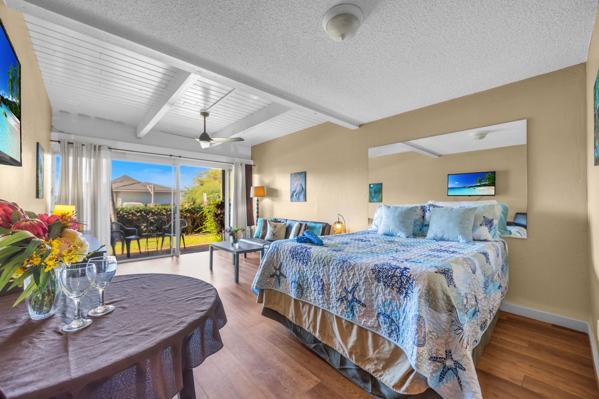 715 South Kihei Road, Unit 107 Kihei, HI 96753 - Photo 6 of 29 a bedroom with a bed a large window with table and chairs