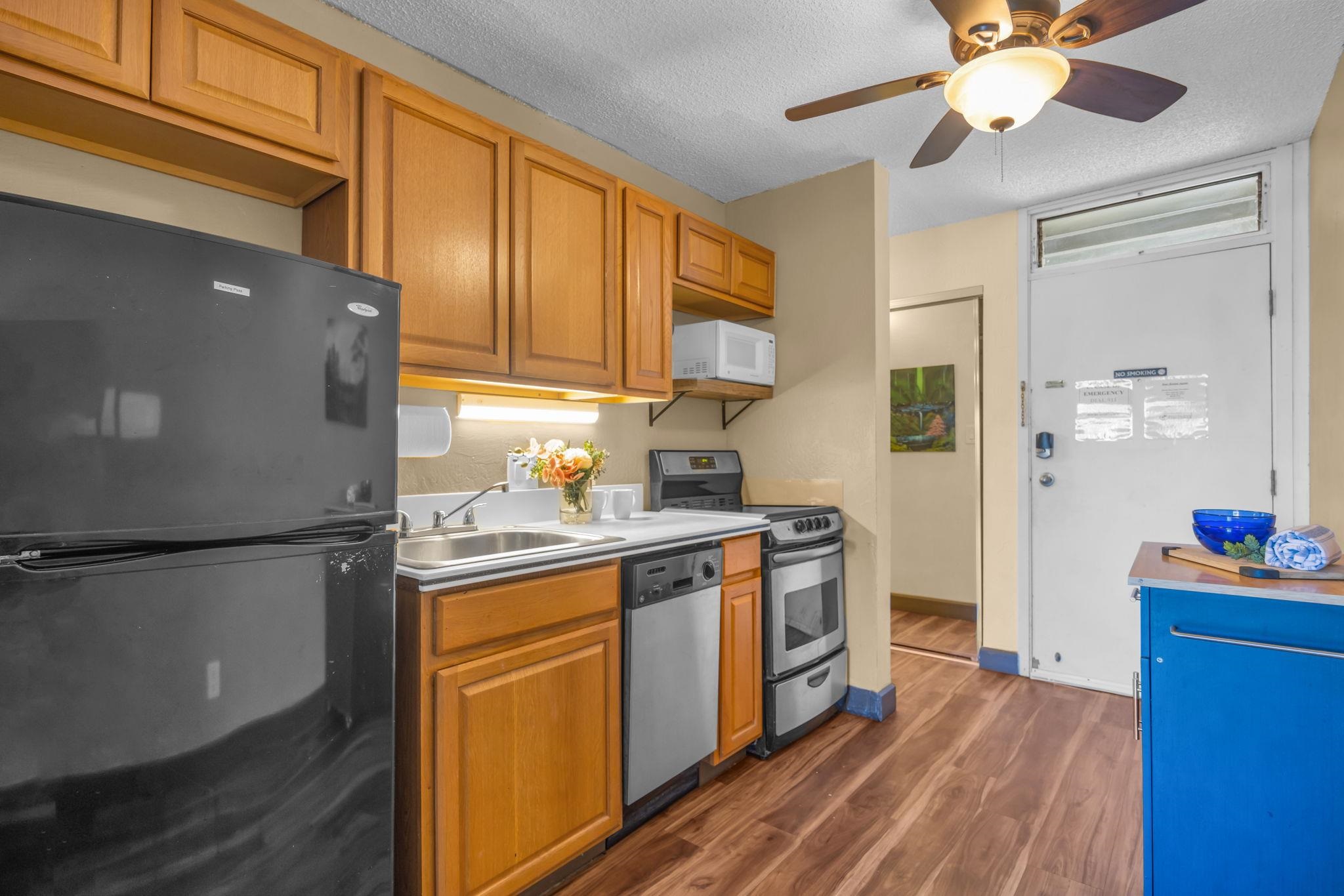 715 South Kihei Road, Unit 107 Kihei, HI 96753 - Photo 9 of 29 a kitchen with stainless steel appliances granite countertop a refrigerator a sink dishwasher a stove and white countertops with wooden floor