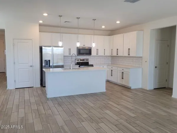 a large kitchen with stainless steel appliances kitchen island a large counter top and a stove top oven