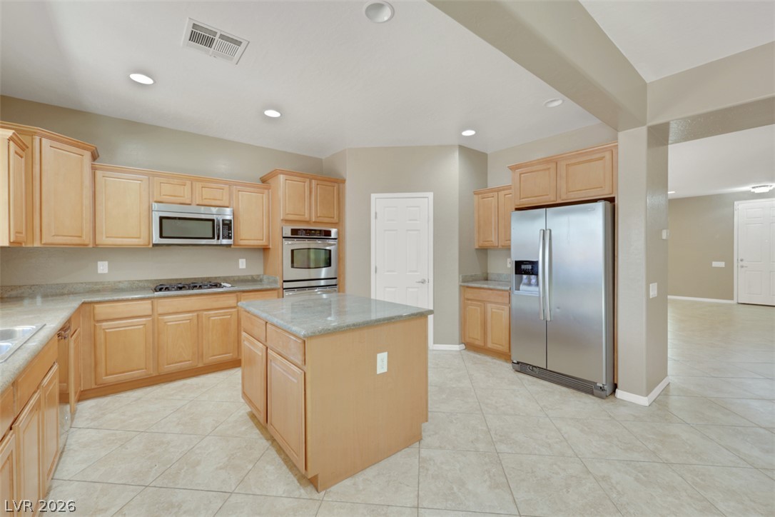2501 Bechamel Place Henderson, NV 89044 - Photo 7 of 50 A functional kitchen features an island, ample cabinetry, and integrated appliances, perfect for daily living.