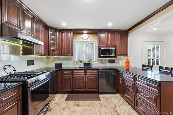 a kitchen with stainless steel appliances granite countertop wooden cabinets a stove top oven a sink and dishwasher