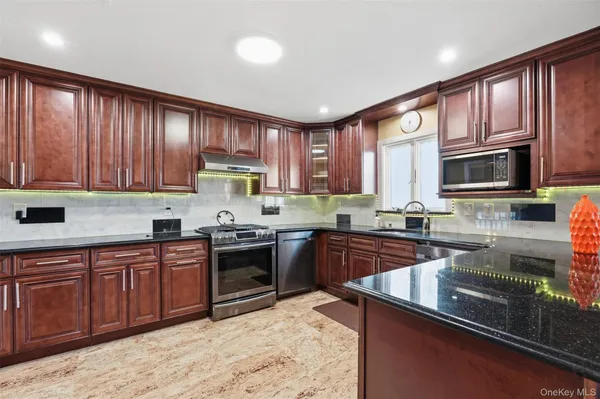 a kitchen with kitchen island granite countertop wooden cabinets stainless steel appliances a sink and a window