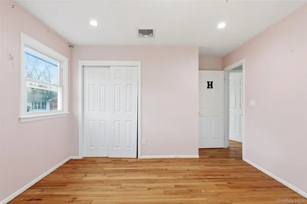 a view of an empty room with window and wooden floor