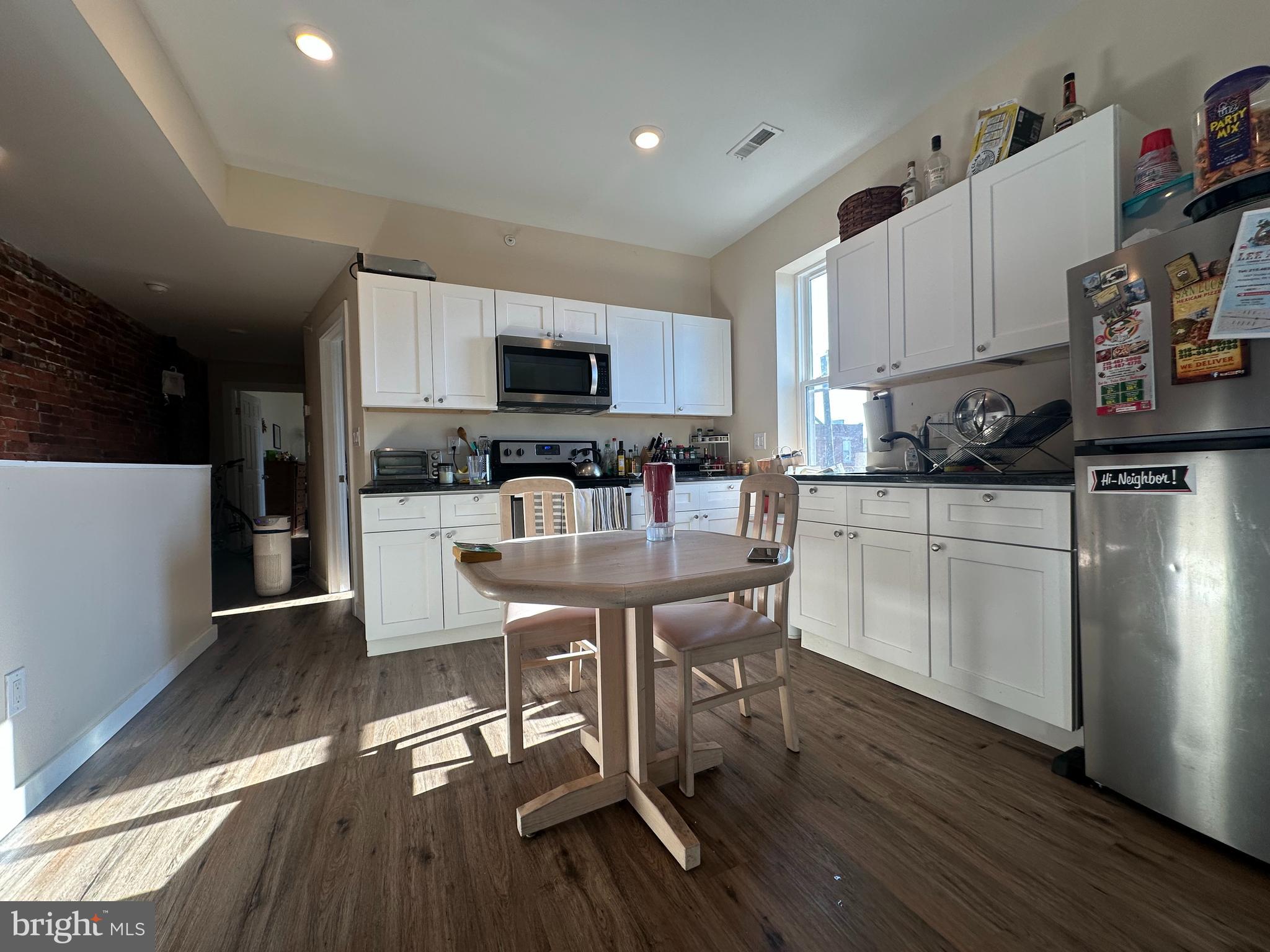1648 South 16th Street, Unit 2 Philadelphia, PA 19145 - Photo 5 of 10 a kitchen with stainless steel appliances a dining table chairs microwave and sink