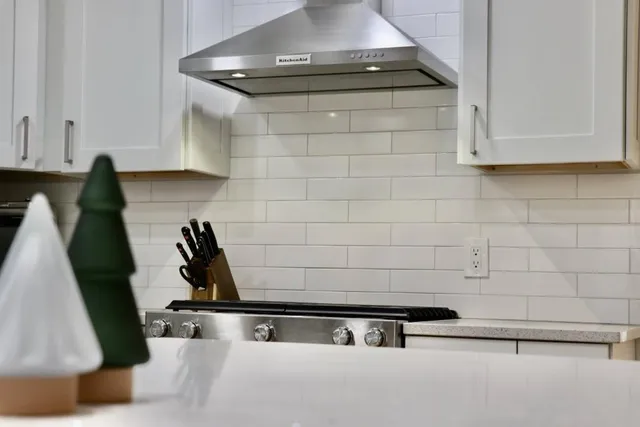 a kitchen with stainless steel appliances granite countertop a sink a refrigerator and white cabinets
