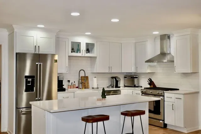 a kitchen with stainless steel appliances granite countertop a refrigerator a sink a stove a microwave and white cabinets