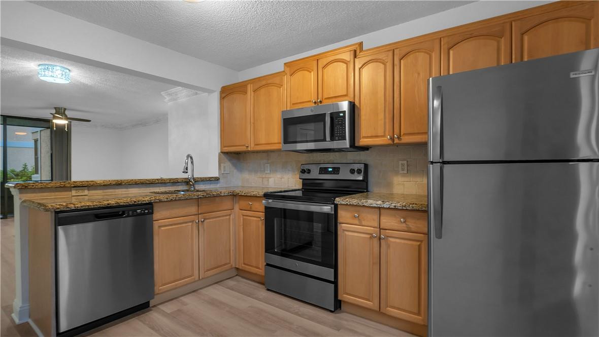 5681 Riverside Drive, Unit 101A6 Coral Springs, FL 33067 - Photo 9 of 25 a kitchen with stainless steel appliances a refrigerator sink and microwave
