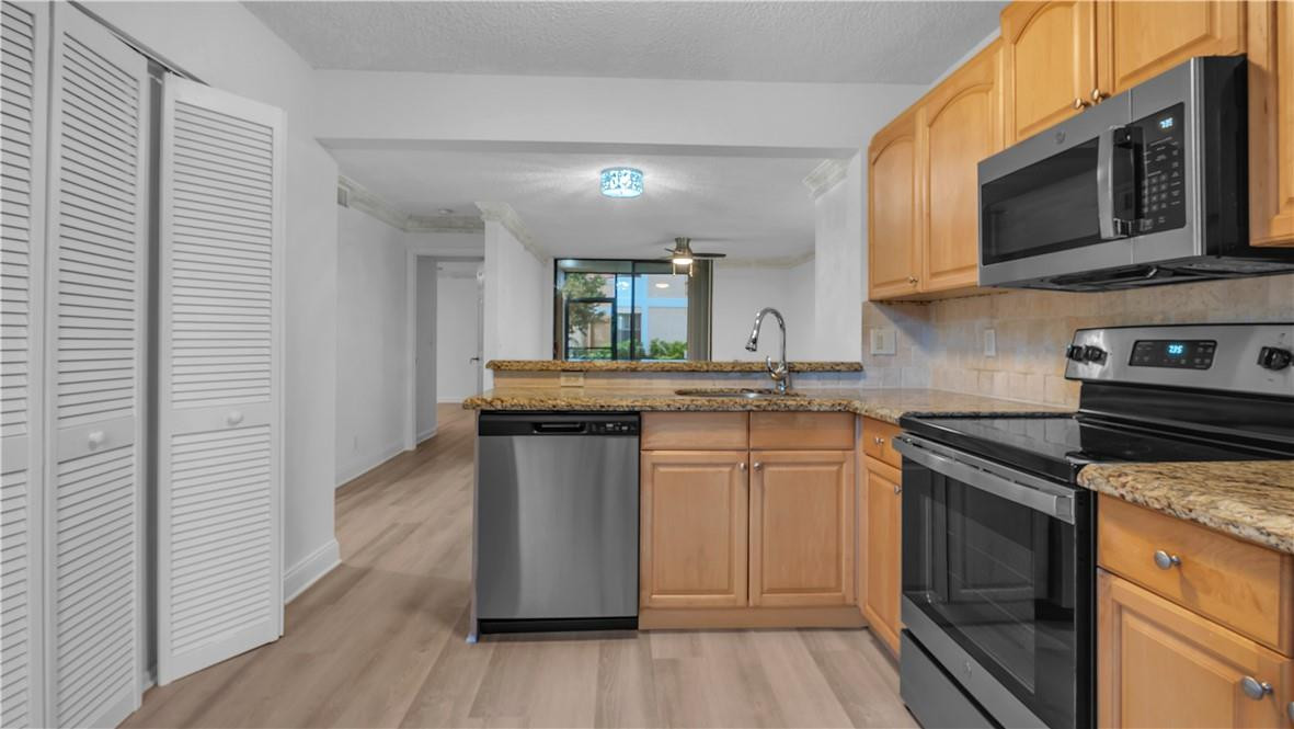 5681 Riverside Drive, Unit 101A6 Coral Springs, FL 33067 - Photo 10 of 25 a kitchen with stainless steel appliances granite countertop a stove a sink and a microwave
