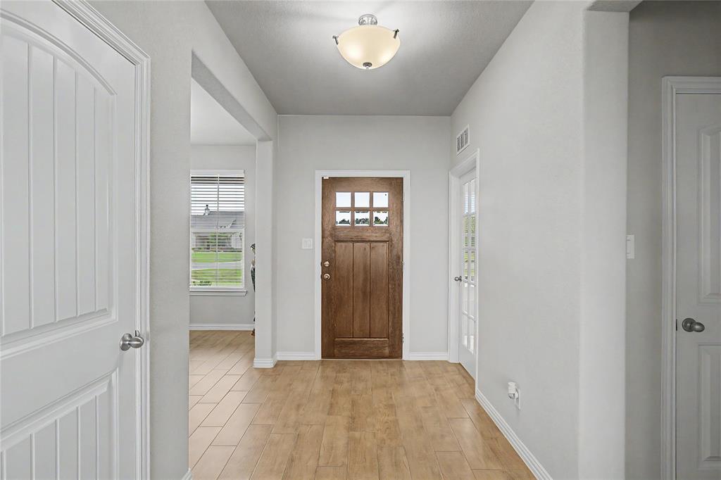 185 Chester Road Springtown, TX 76082 - Photo 9 of 40 Entryway featuring wood-finish flooring, a six-paneled wood entry door, and a semi-flush mount ceiling light