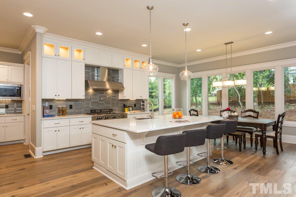 3208 Cobblestone Court Raleigh, NC 27607 - Photo 5 of 25 a kitchen with a dining table chairs sink and white cabinets