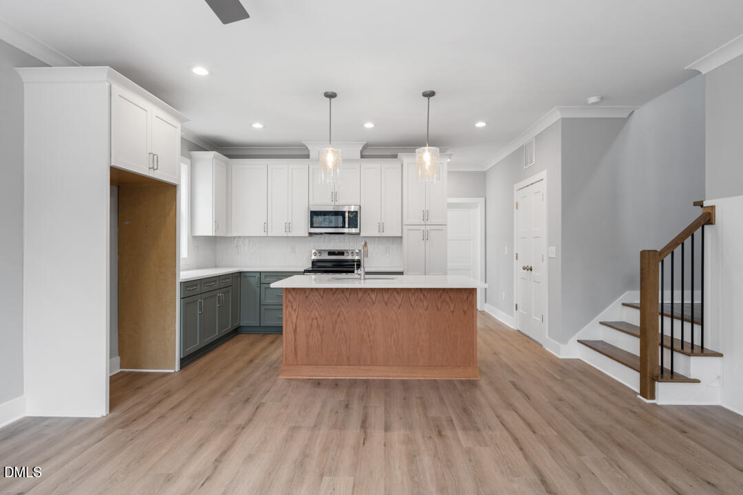 a large kitchen with stainless steel appliances kitchen island a large counter top and wooden floors
