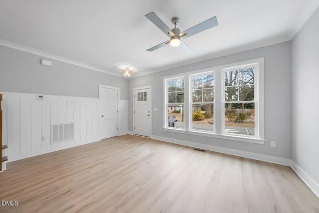 an empty room with wooden floor and windows