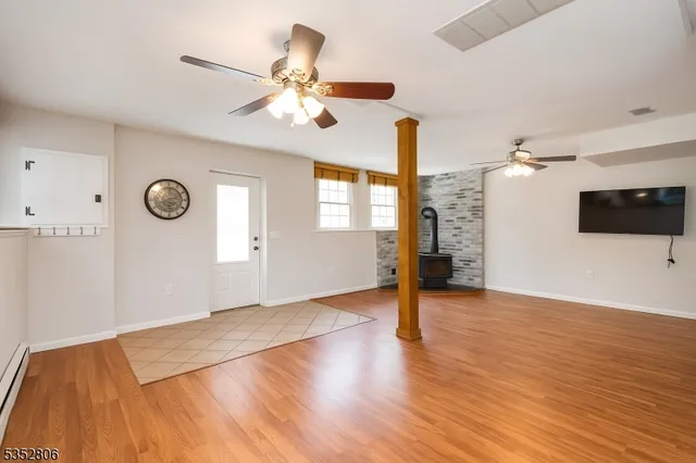 a view of an empty room with wooden floor and a ceiling fan